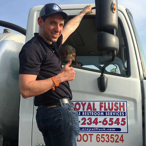 image of a smiling A Royal Flush service technician hanging on to the side of their service truck